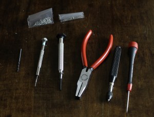 Poranterä, "Tap"-työkalu, “star-nut spanner”, "de-riveting”-työkalu, "universal holder" ja ruuvimeisseli. Ylhäällä vaihtoruuveja ja vastakappaleita.